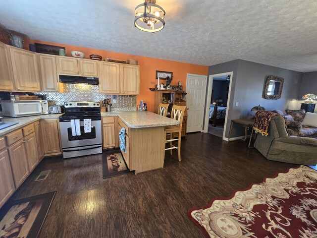 kitchen featuring white microwave, a peninsula, dark wood-style flooring, stainless steel range with electric stovetop, and under cabinet range hood