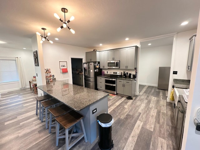 kitchen with kitchen peninsula, stainless steel appliances, gray cabinetry, pendant lighting, and a breakfast bar