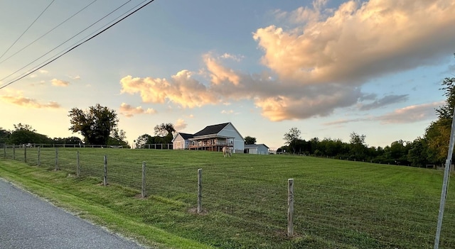 yard at dusk featuring a rural view