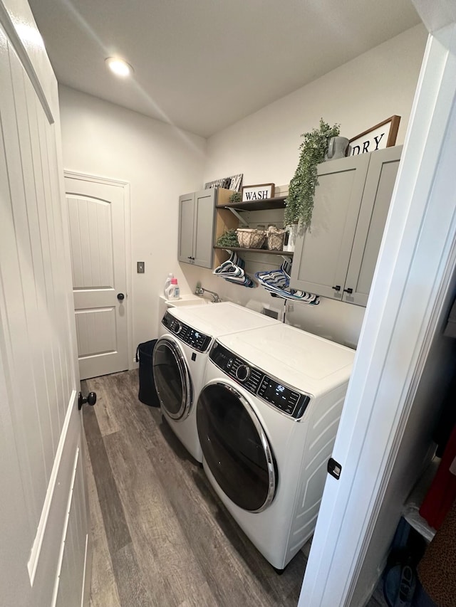 clothes washing area with washer and clothes dryer, cabinets, and dark hardwood / wood-style floors