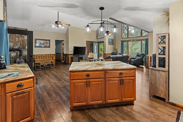 kitchen with a wood stove, ceiling fan, dark hardwood / wood-style floors, pendant lighting, and a kitchen island