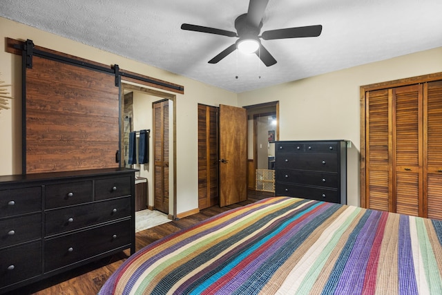 bedroom with ceiling fan, a barn door, and two closets