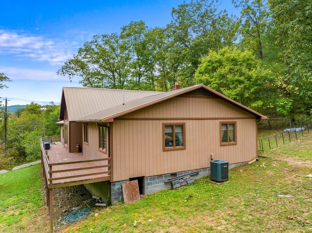 view of property exterior with a lawn, central air condition unit, and a wooden deck