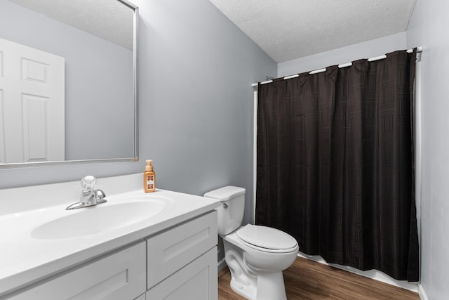 bathroom featuring a shower with shower curtain, vanity, a textured ceiling, wood-type flooring, and toilet