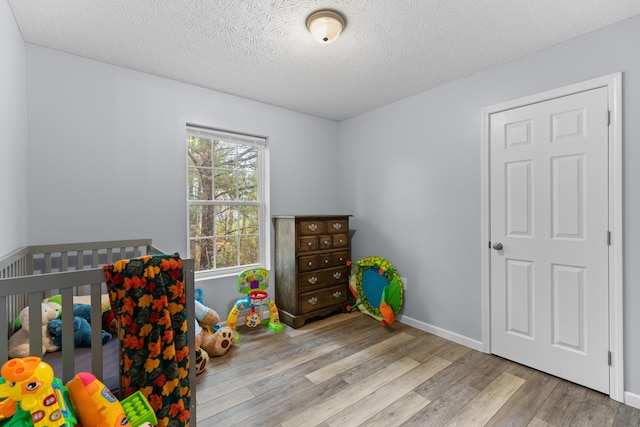 bedroom featuring a textured ceiling, a crib, and light wood-type flooring