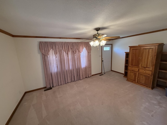 unfurnished room featuring light colored carpet, crown molding, a textured ceiling, and baseboards