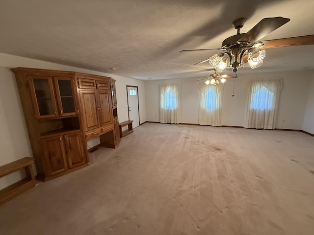 unfurnished living room with light carpet, ceiling fan, a textured ceiling, and baseboards