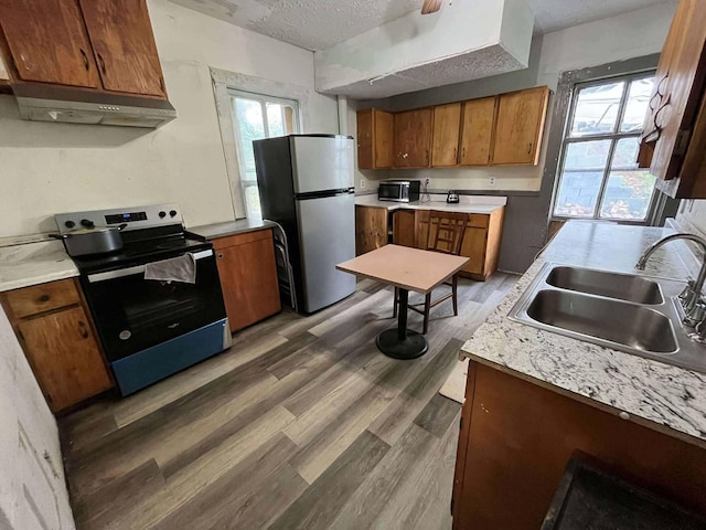 207 E 2nd N St, Morristown, TN 37814 - kitchen featuring stainless steel appliances, under cabinet range hood, brown cabinetry, light countertops, and a textured ceiling