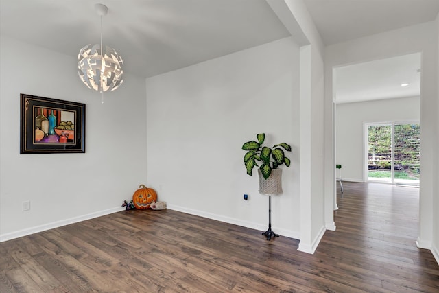 unfurnished room featuring dark wood-type flooring and a chandelier