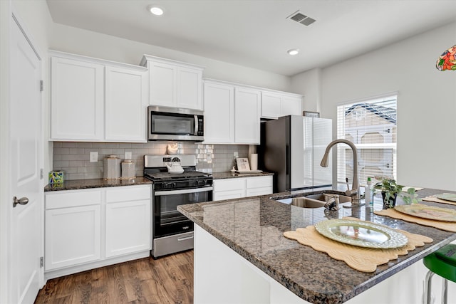 kitchen with dark wood-type flooring, sink, dark stone countertops, white cabinetry, and stainless steel appliances