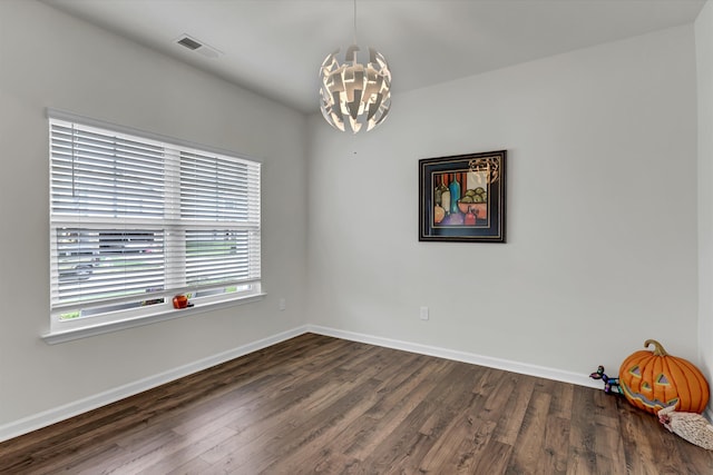 unfurnished room with a notable chandelier and dark hardwood / wood-style floors