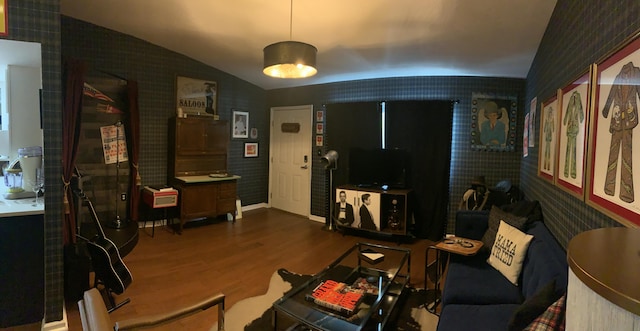 living room with wallpapered walls, wood finished floors, and vaulted ceiling