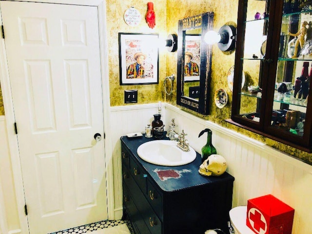 half bath featuring vanity and a wainscoted wall