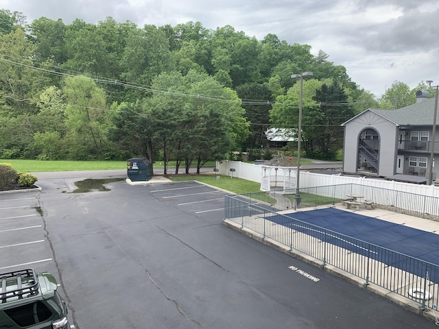 view of vehicle parking featuring a fenced in pool and fence