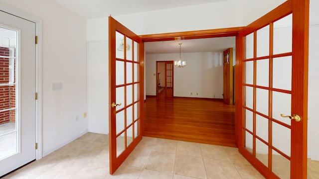 hall with french doors, light tile patterned floors, and an inviting chandelier