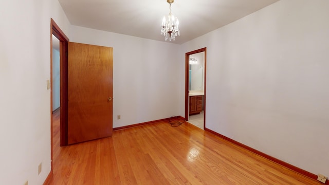 unfurnished room with light hardwood / wood-style flooring and an inviting chandelier