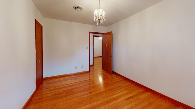 unfurnished room featuring light hardwood / wood-style flooring and a chandelier