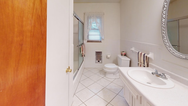 full bathroom featuring combined bath / shower with glass door, vanity, heating unit, tile walls, and tile patterned flooring