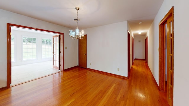 spare room with hardwood / wood-style flooring and a notable chandelier