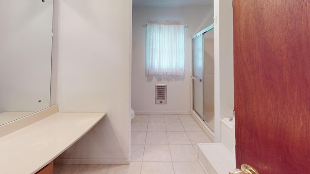 bathroom with tile patterned floors, heating unit, toilet, vanity, and a shower with shower door