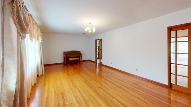 spare room with light hardwood / wood-style flooring and a notable chandelier