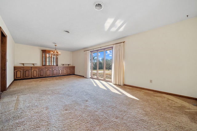 carpeted empty room featuring a chandelier