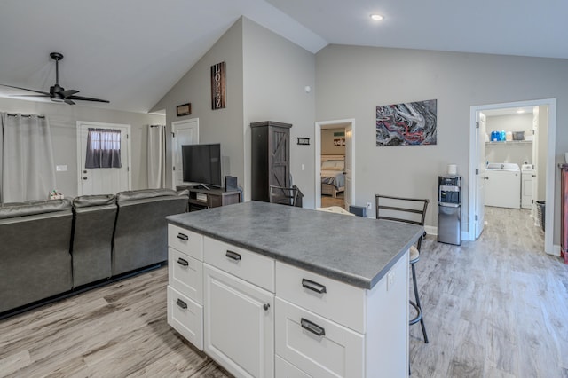 kitchen with a kitchen island, ceiling fan, washer and dryer, light hardwood / wood-style flooring, and white cabinetry