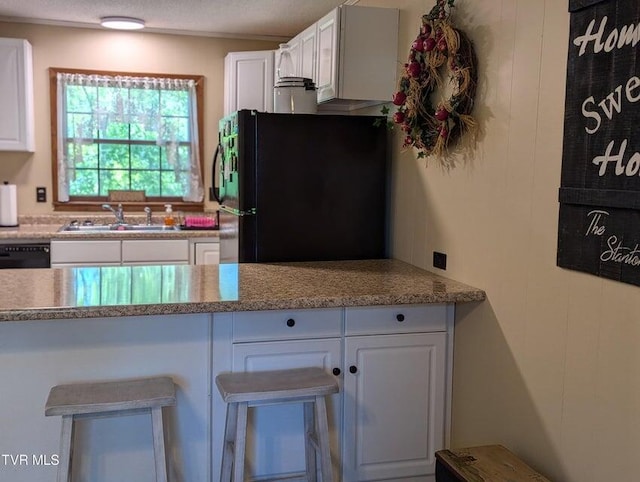 kitchen featuring black appliances, white cabinetry, and sink