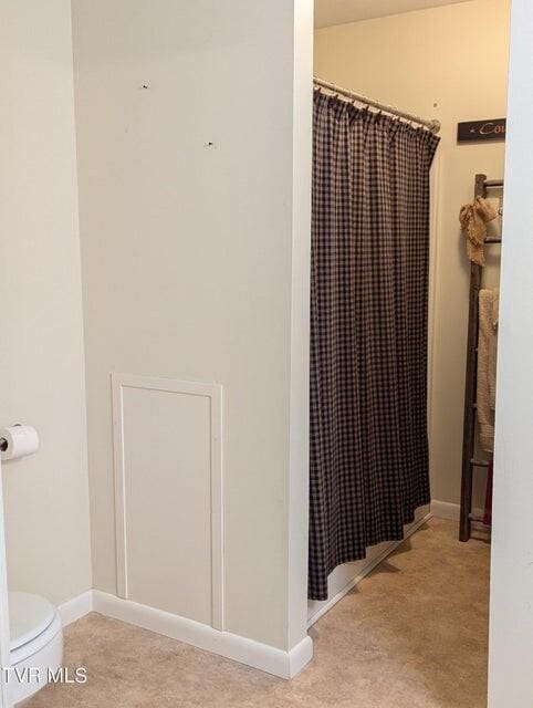 bathroom with a shower with shower curtain and toilet