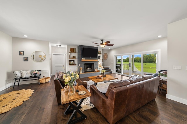 living room featuring a large fireplace, dark hardwood / wood-style floors, and ceiling fan