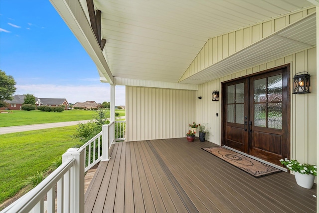 wooden terrace featuring covered porch, a yard, and french doors