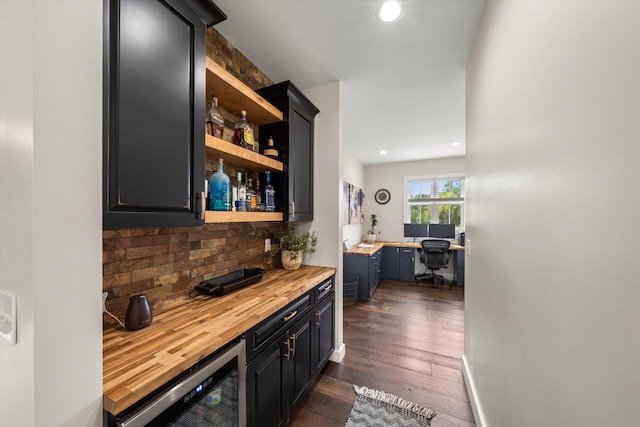 bar with backsplash, wine cooler, dark hardwood / wood-style floors, built in desk, and butcher block counters