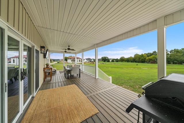 wooden deck featuring grilling area, ceiling fan, and a yard