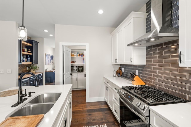 kitchen with white cabinetry, sink, hanging light fixtures, wall chimney range hood, and stainless steel gas range