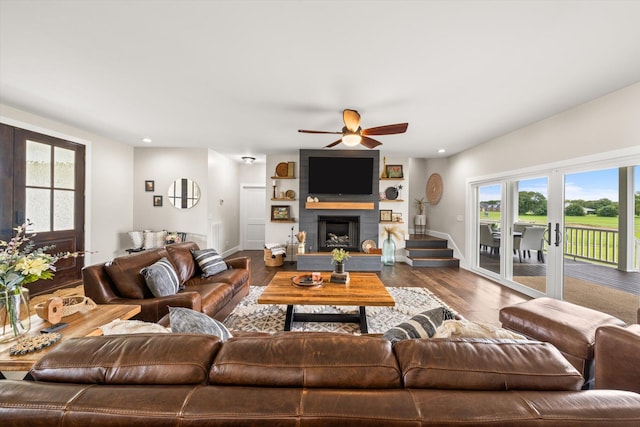 living room featuring hardwood / wood-style floors, a large fireplace, and ceiling fan