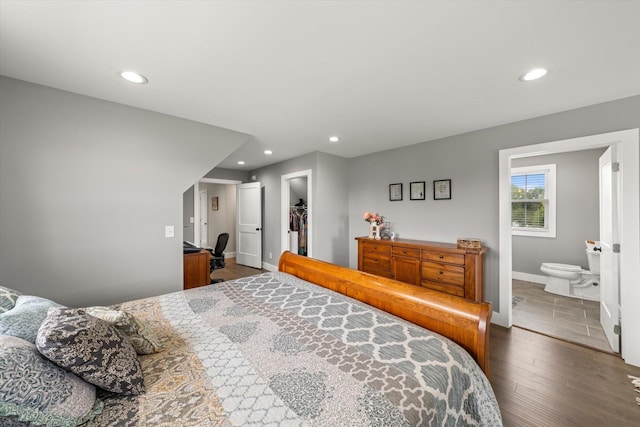 bedroom featuring ensuite bath, a walk in closet, a closet, and dark wood-type flooring