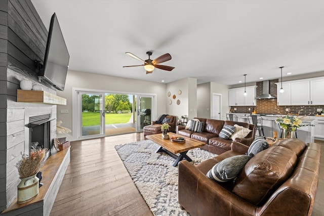 living room with ceiling fan, a high end fireplace, and light hardwood / wood-style floors