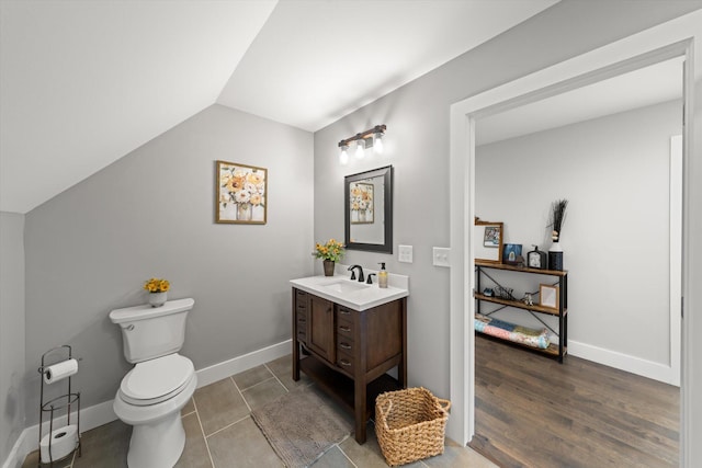 bathroom featuring vanity, toilet, and lofted ceiling