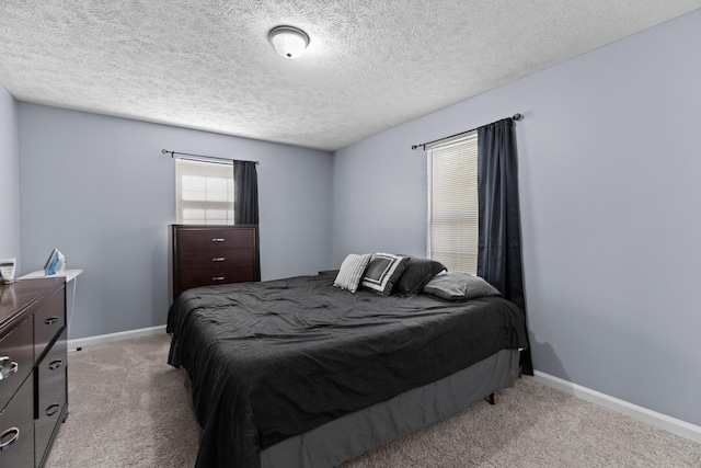 bedroom with light colored carpet, a textured ceiling, and baseboards