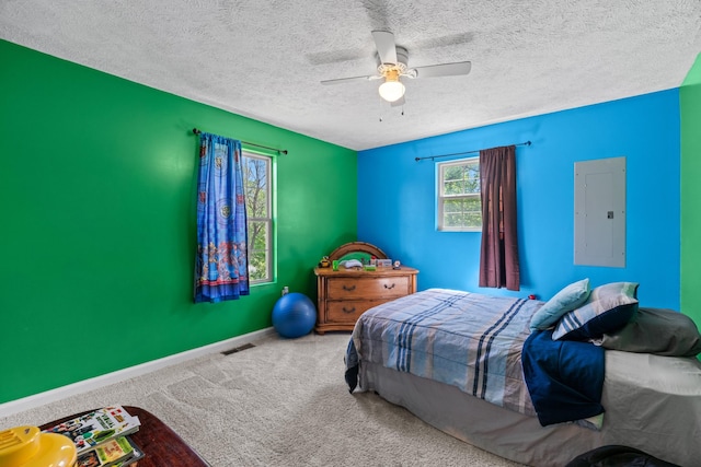 carpeted bedroom featuring ceiling fan, a textured ceiling, baseboards, visible vents, and electric panel