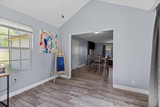 foyer entrance with baseboards, wood finished floors, and high vaulted ceiling