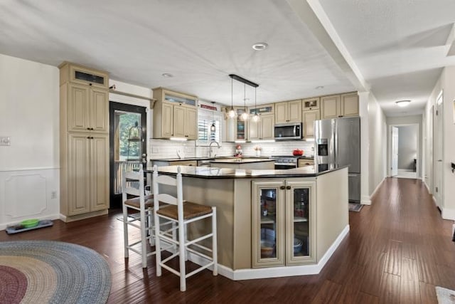 1626 Cardinal Dr, Morristown, TN 37814 - kitchen with dark countertops, glass insert cabinets, a center island, cream cabinetry, and appliances with stainless steel finishes