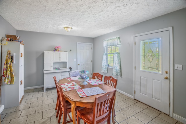 dining area with baseboards, a textured ceiling, and light tile patterned floors