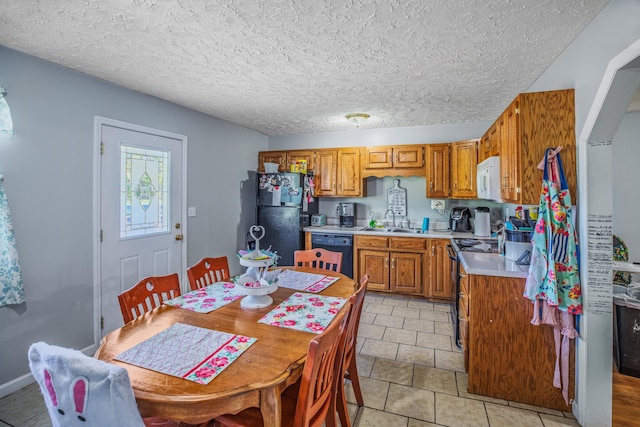 kitchen featuring a sink, light tile patterned flooring, brown cabinetry, light countertops, and black appliances