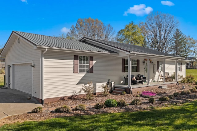 exterior space featuring an attached garage, a porch, concrete driveway, and metal roof
