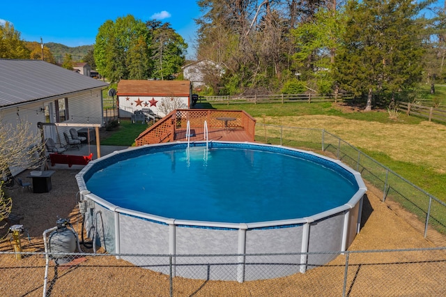 pool featuring a wooden deck, a lawn, and fence private yard