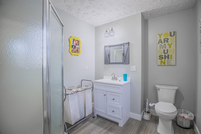 bathroom featuring a textured ceiling, toilet, baseboards, wood finished floors, and vanity