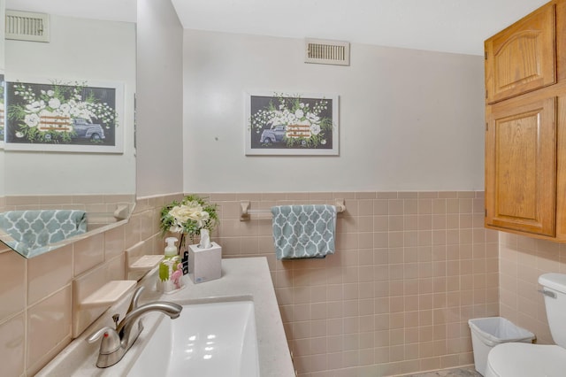 bathroom featuring sink, tile walls, and toilet