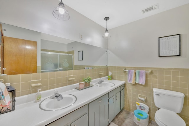 bathroom featuring vanity, toilet, tile walls, and a shower with shower door