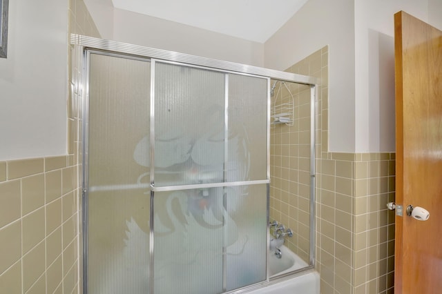 bathroom with enclosed tub / shower combo and tile walls